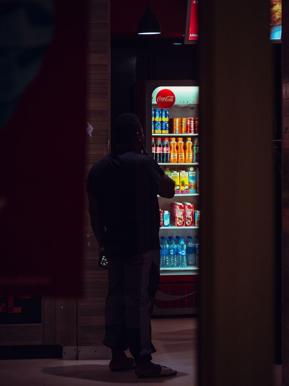 Guest browsing an illuminated smart drink cooler in a dim lounge